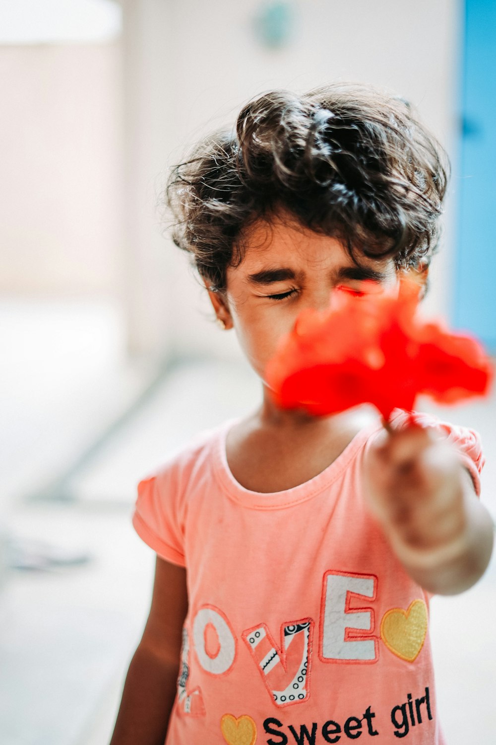 a little girl holding a red flower in her hand