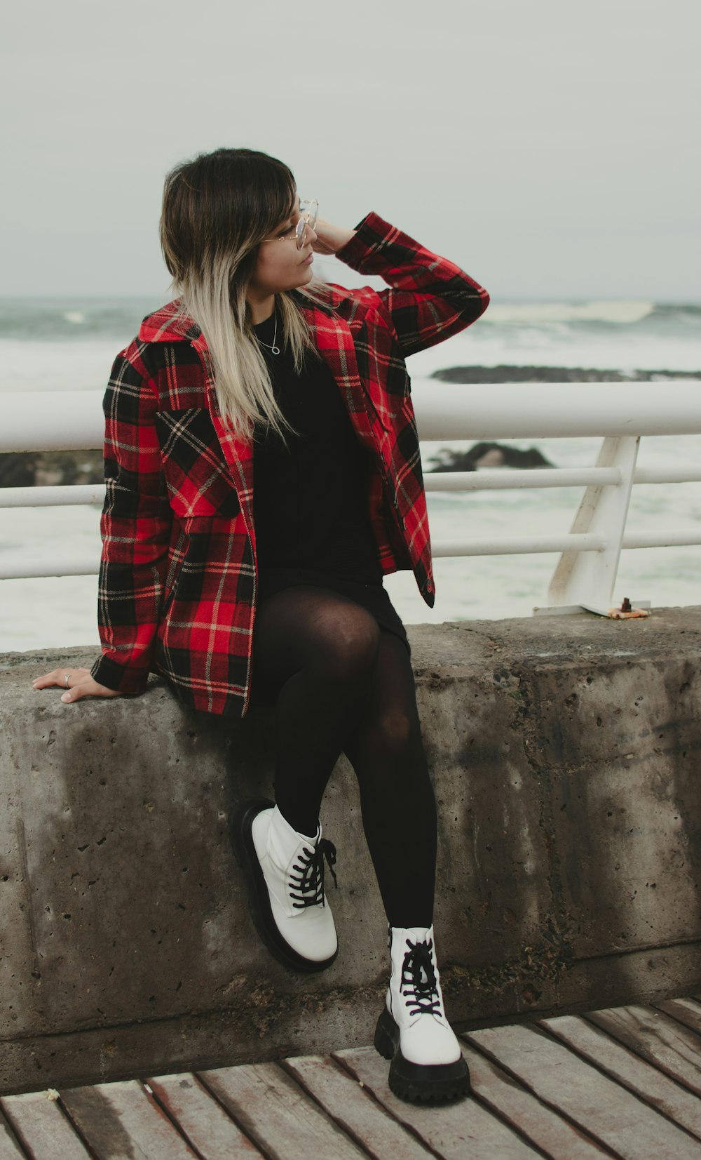 a woman sitting on a wall next to the ocean