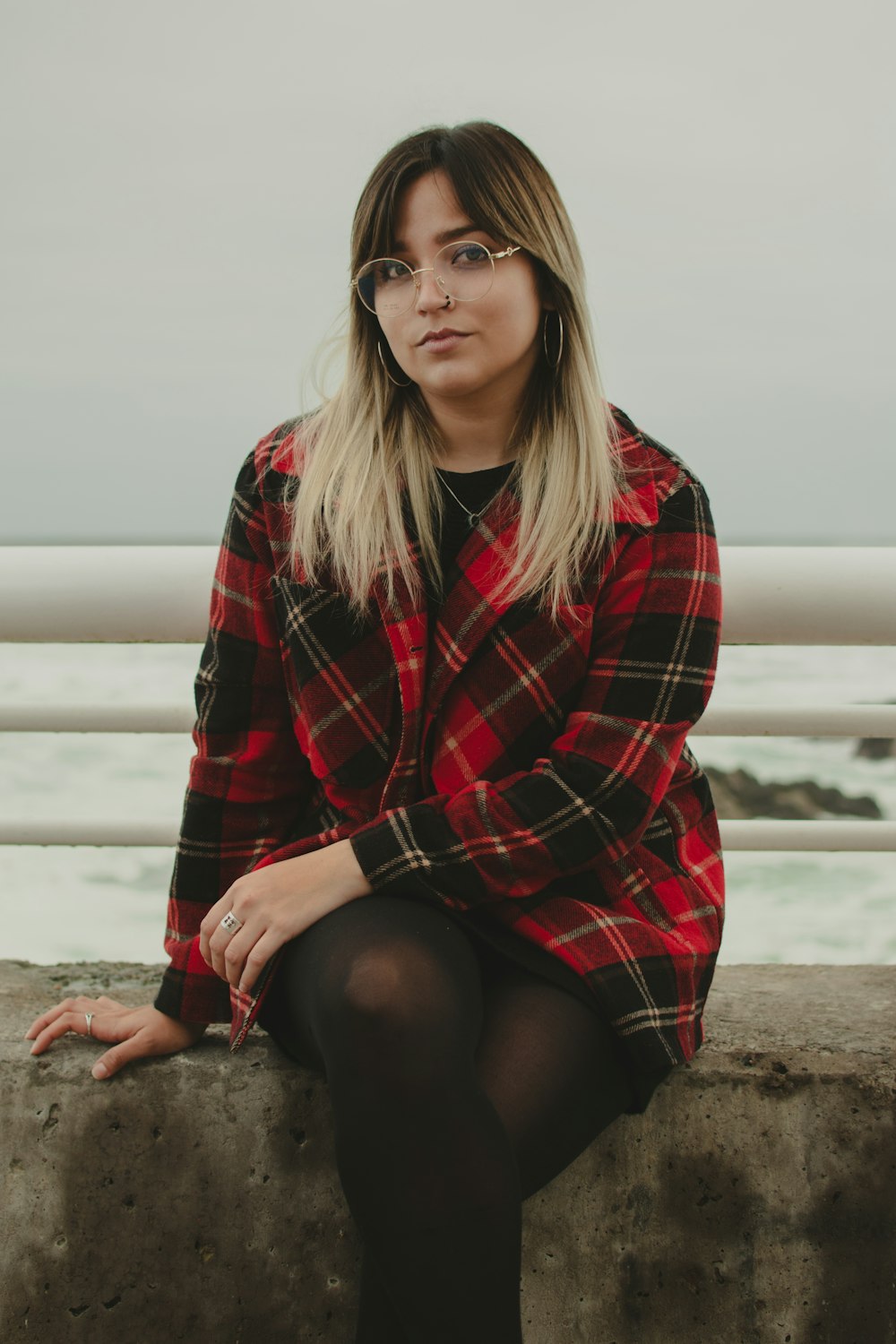 a woman wearing glasses sitting on a wall