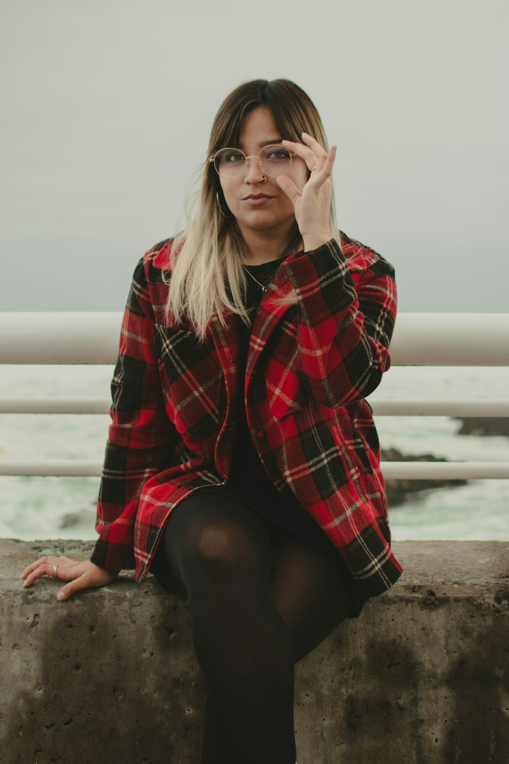 a woman sitting on a wall with her hand on her face