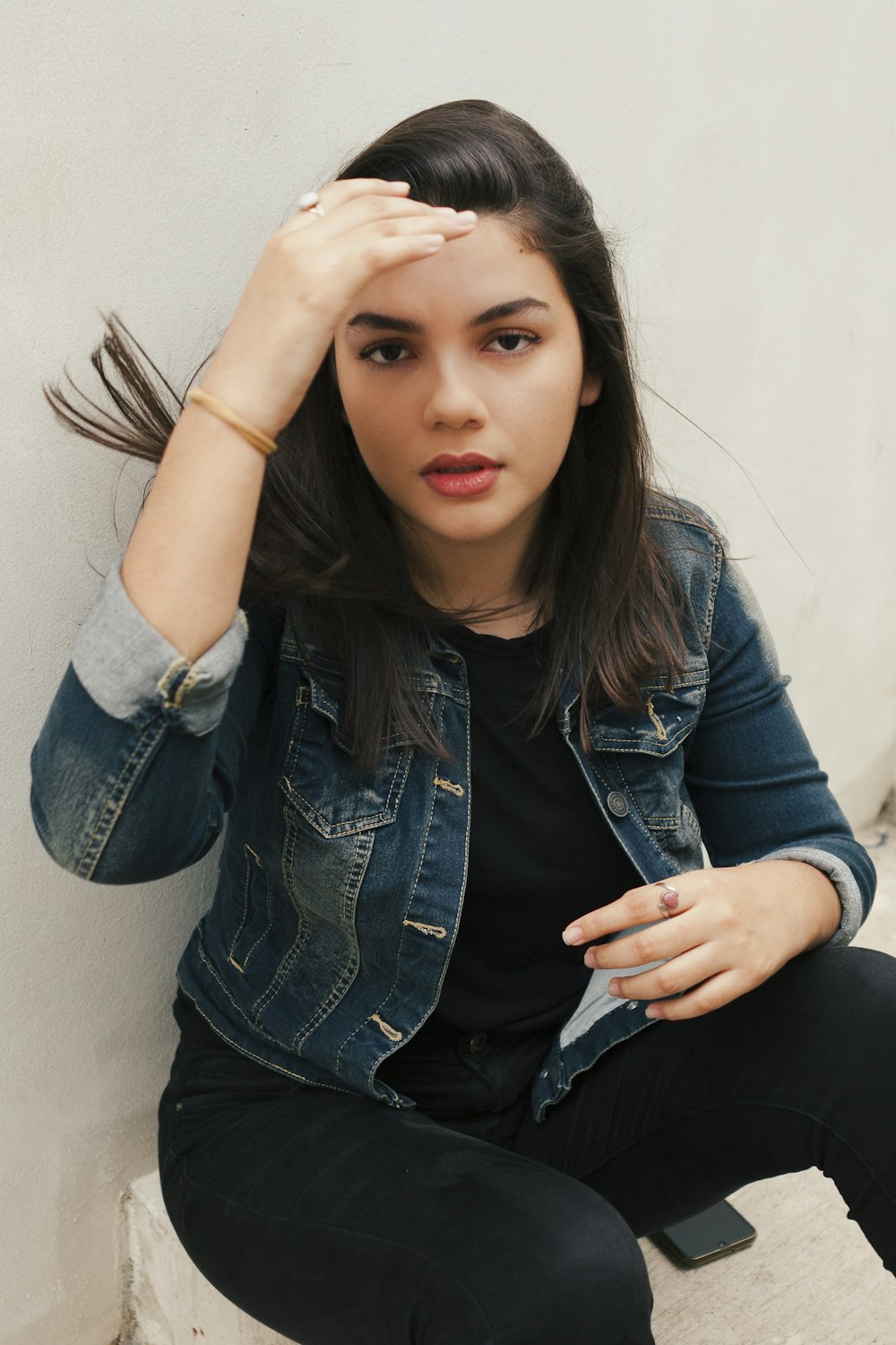 a woman sitting on the ground with her hand on her head