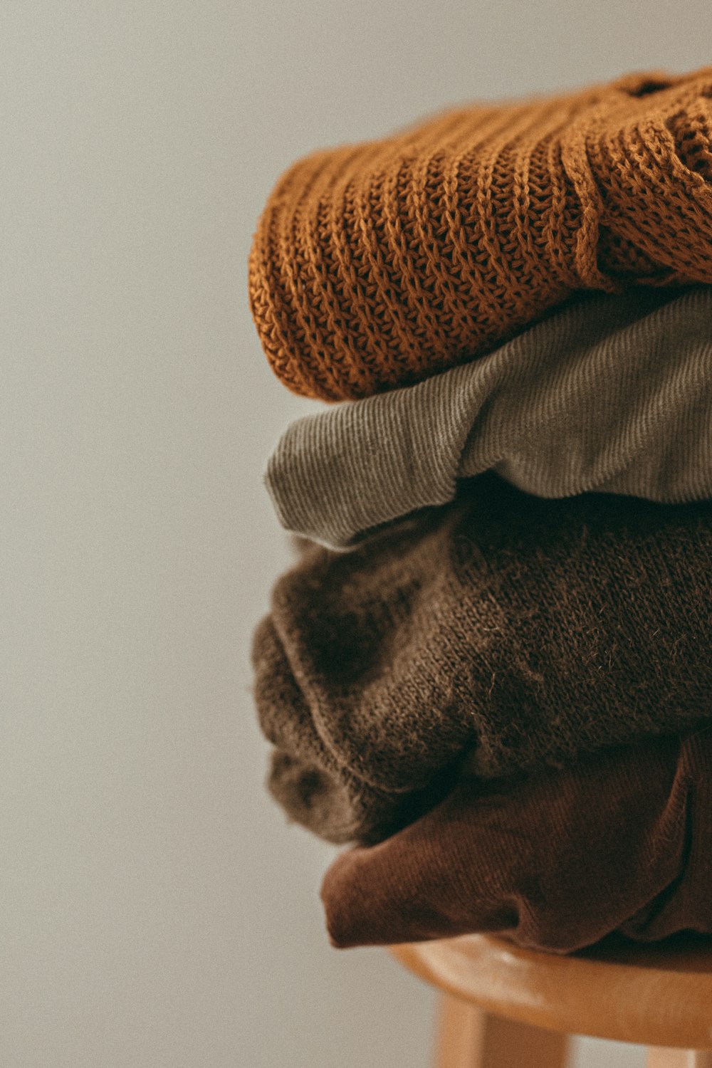 a stack of sweaters sitting on top of a wooden stool