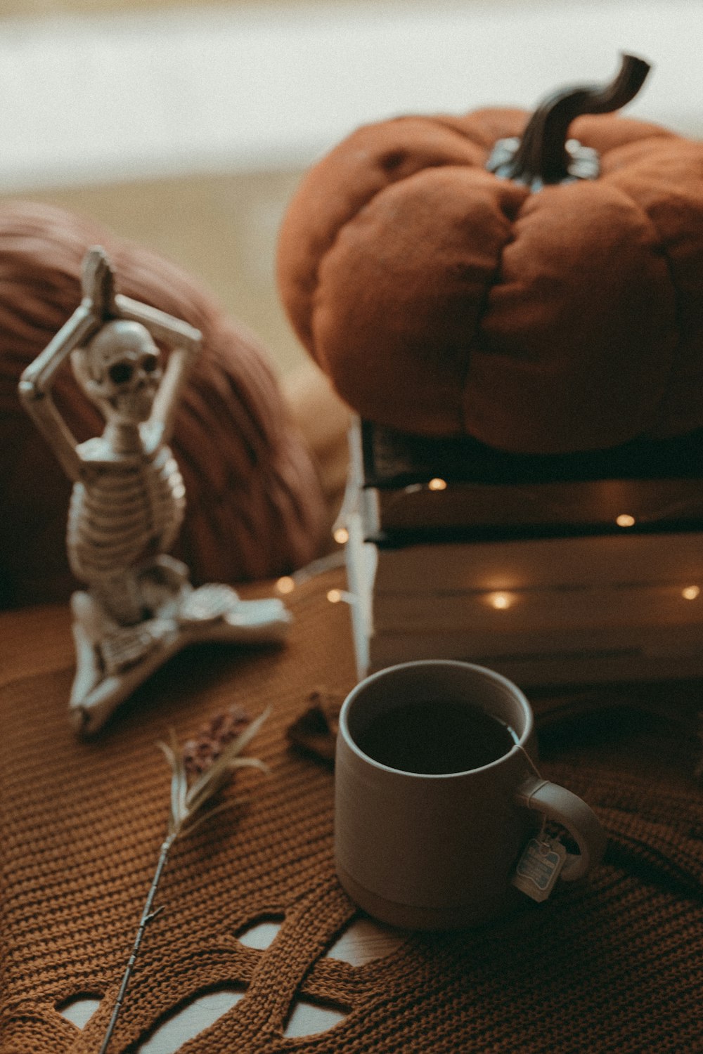 a skeleton figurine sitting on top of a table next to a cup of
