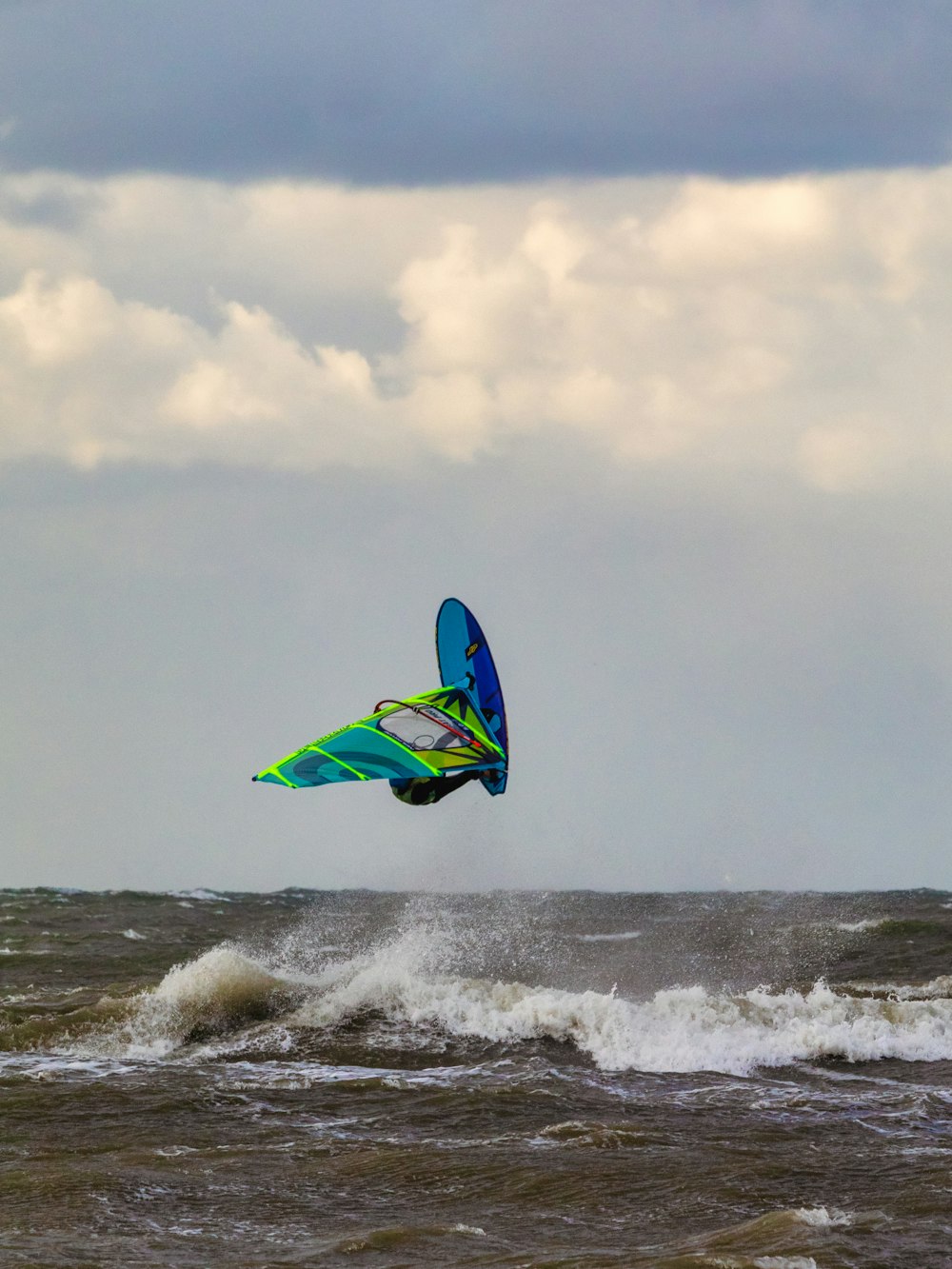 a person windsurfing in the ocean on a cloudy day