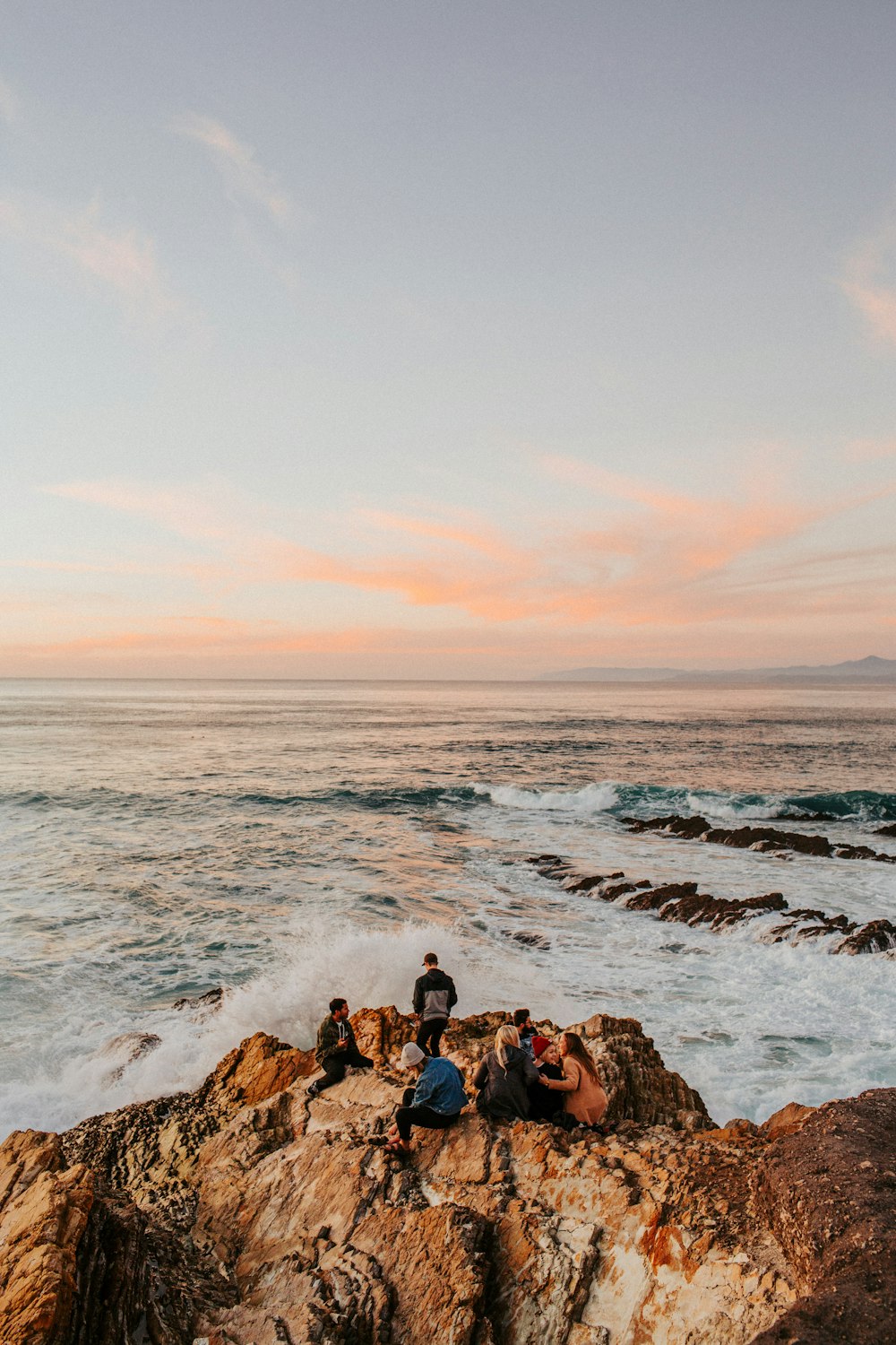 海の隣の岩の上に座っている人々のグループ