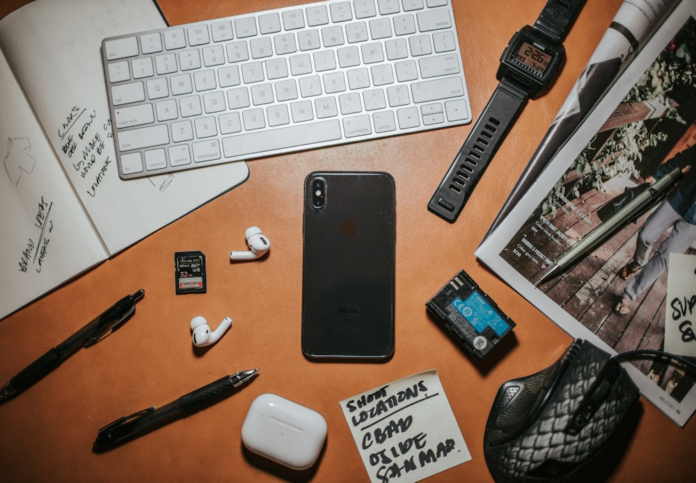 a desk with a keyboard, mouse, cell phone and other items