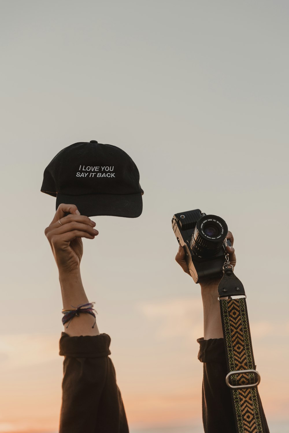two people holding up a hat and a camera
