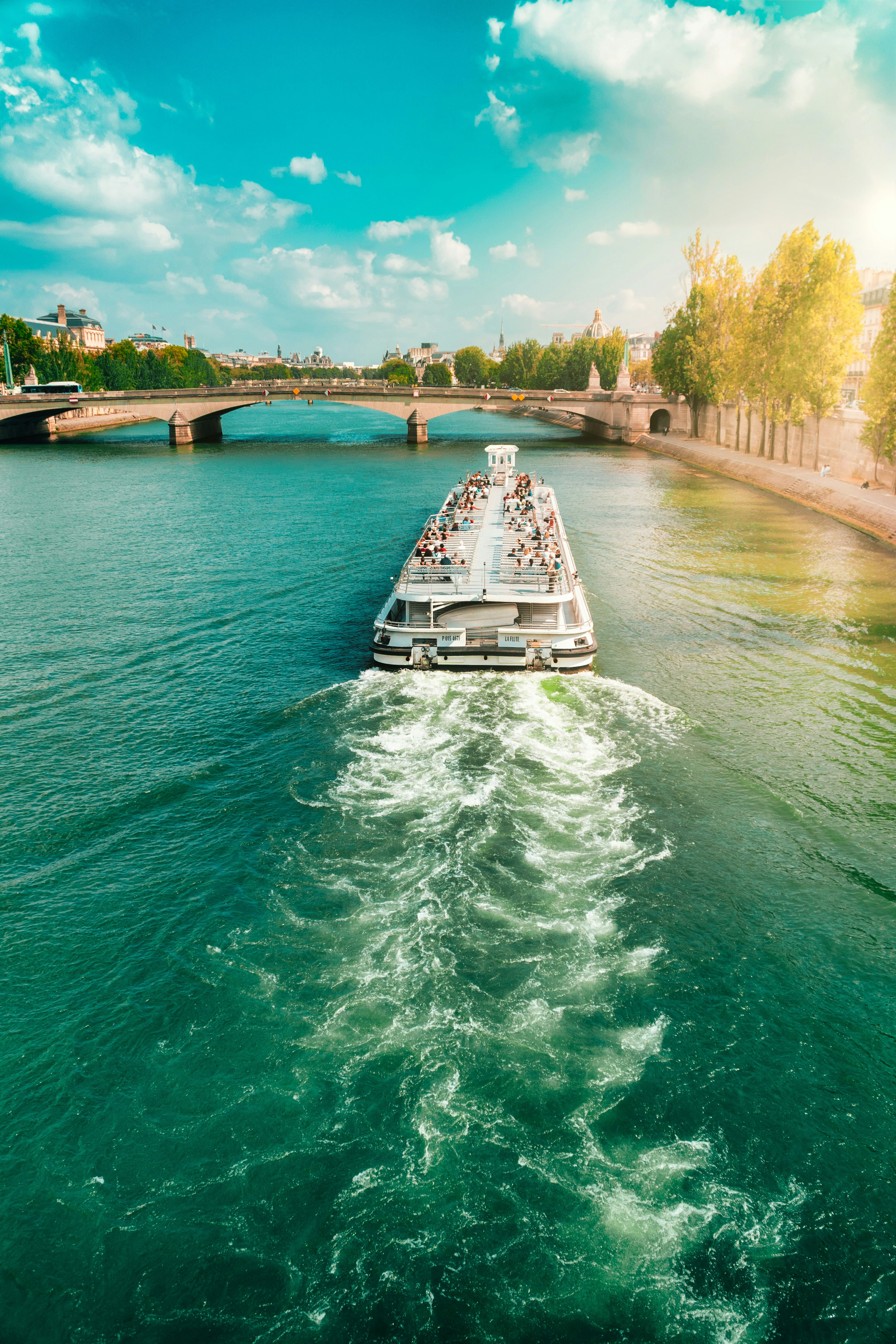 a long boat traveling down a river next to a bridge