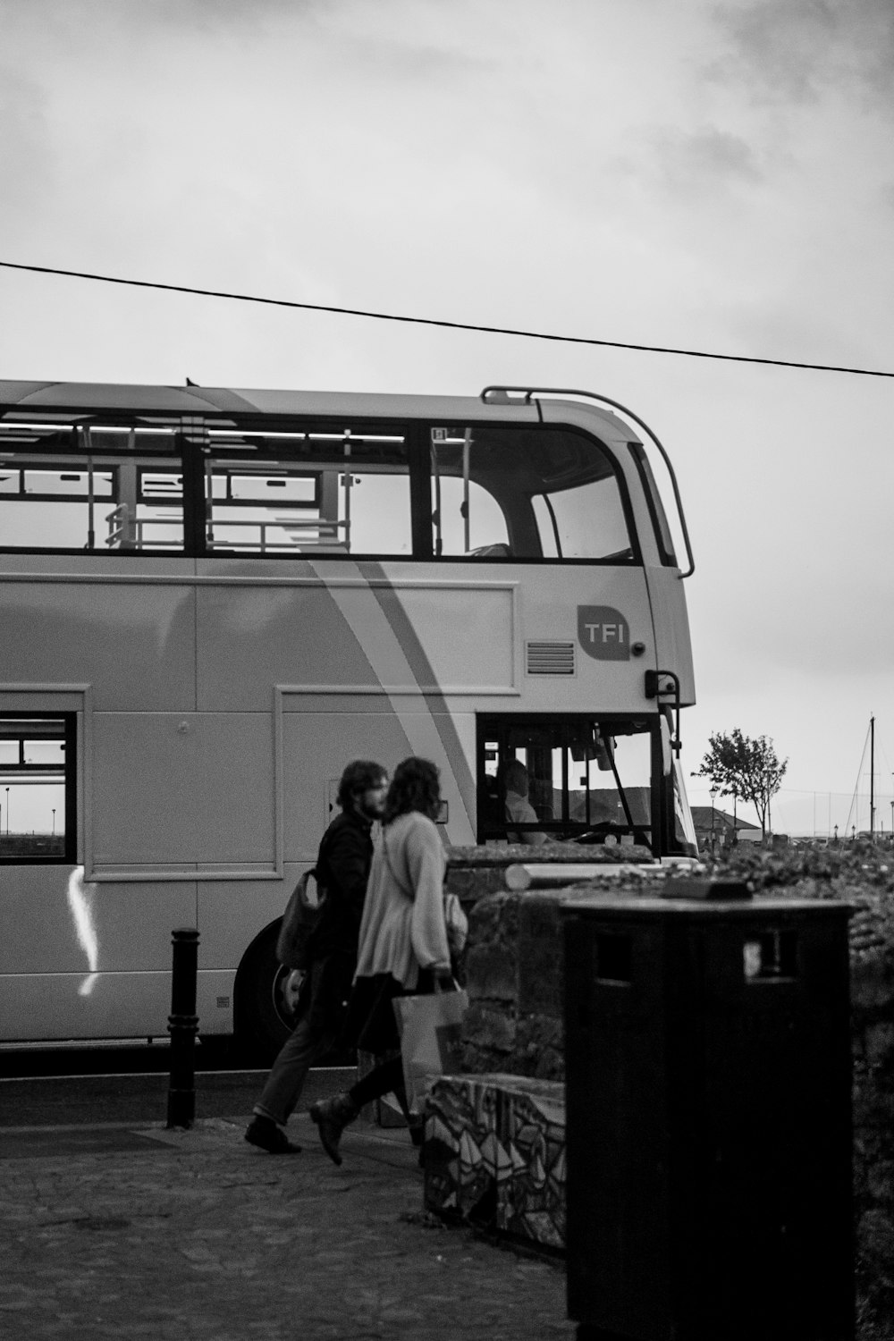 a couple of people walking next to a double decker bus