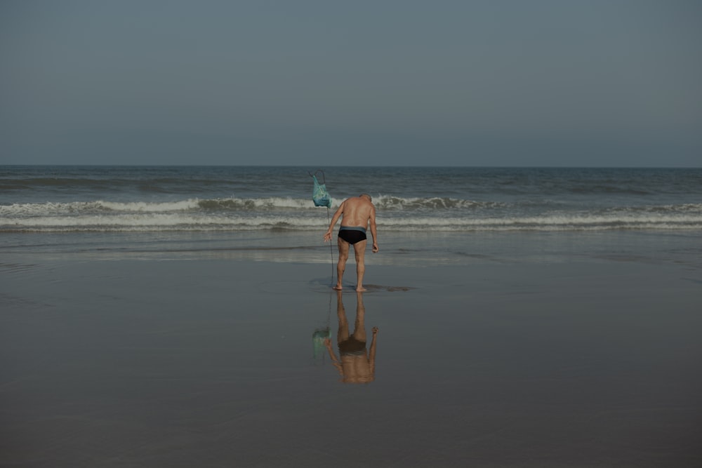 a man standing on top of a beach next to the ocean