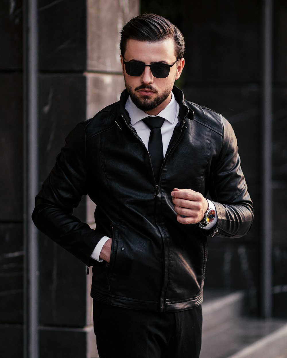 a man wearing a black leather jacket and tie