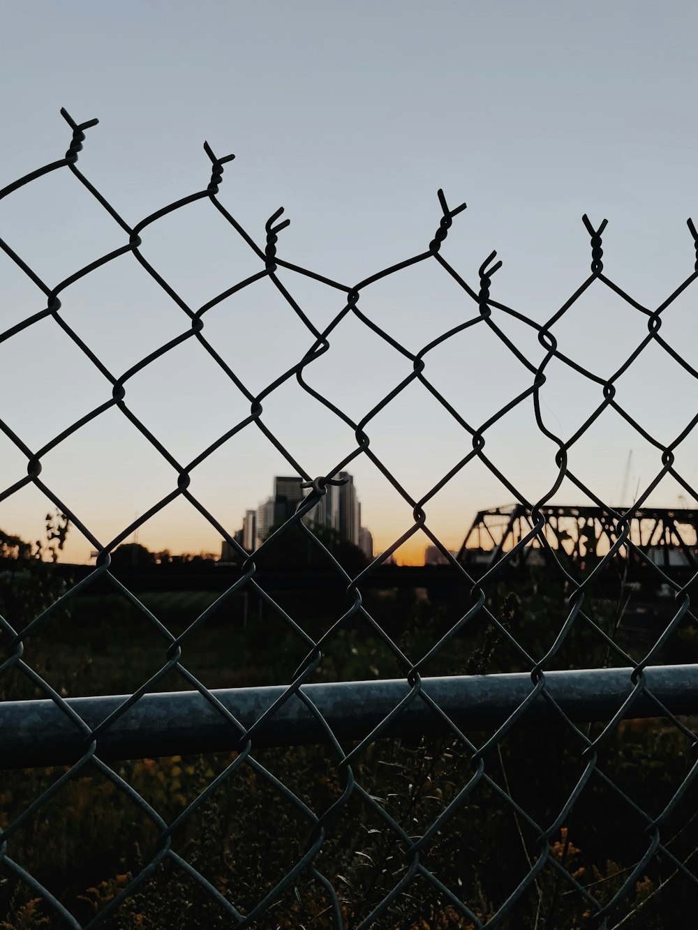 a view of a city through a chain link fence