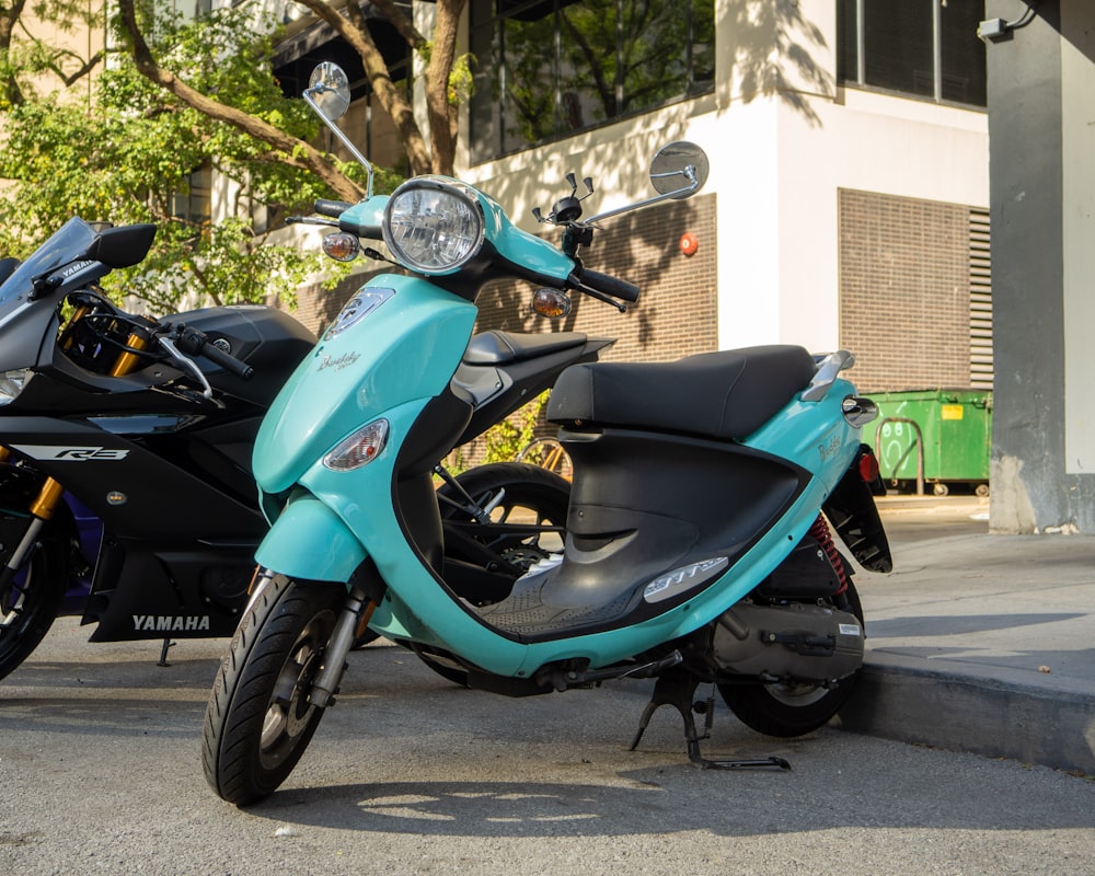 a blue scooter parked next to a black scooter