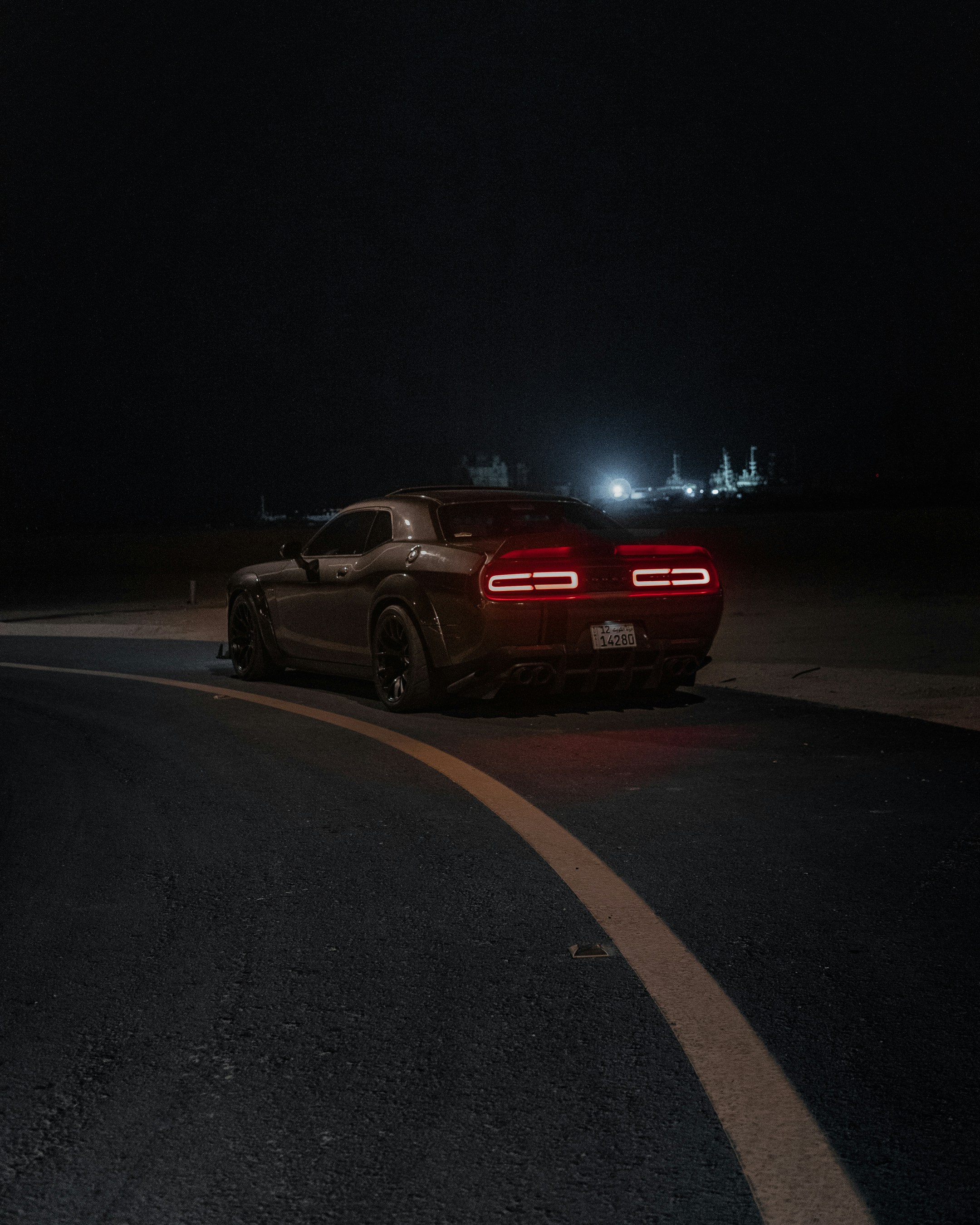 a black sports car driving on a road at night