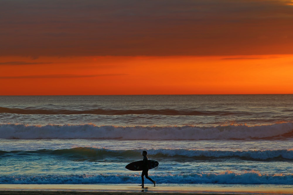 a person walking on the beach with a surfboard