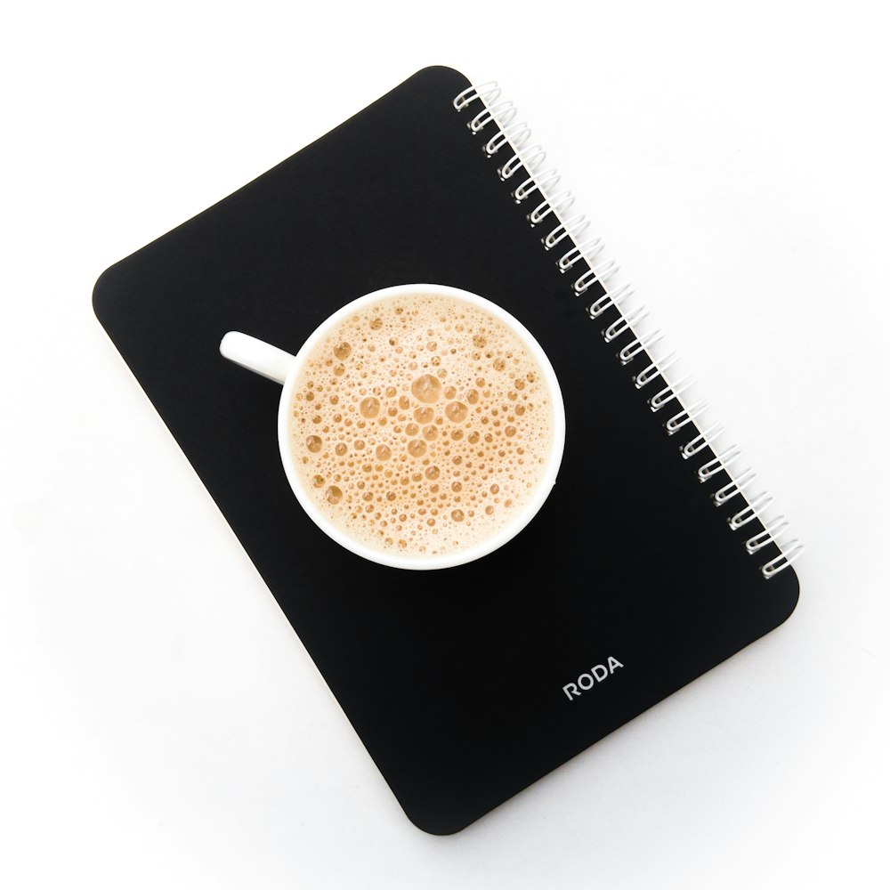 a cup of coffee sitting on top of a notebook