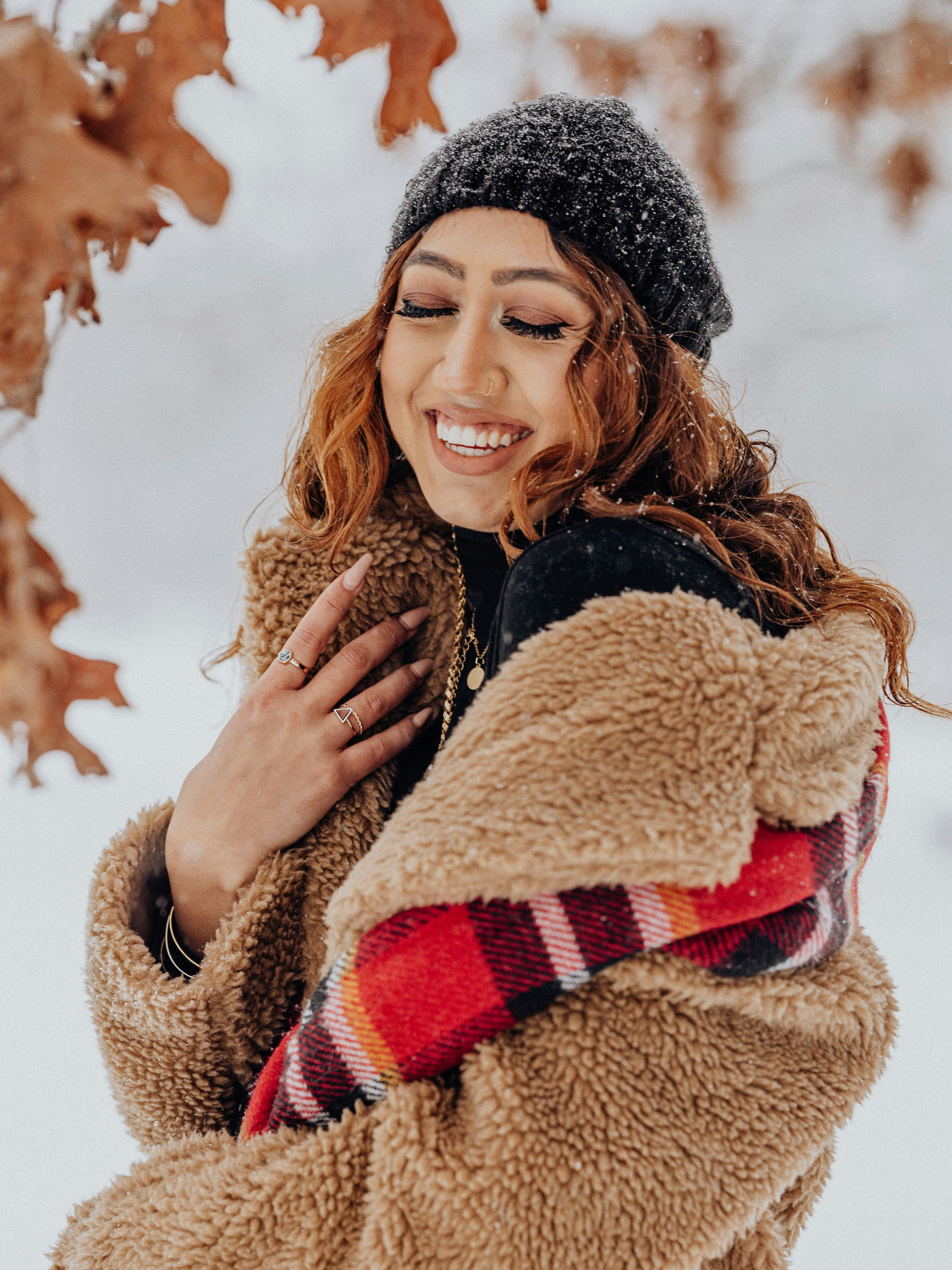 a woman standing in the snow wearing a jacket and a hat