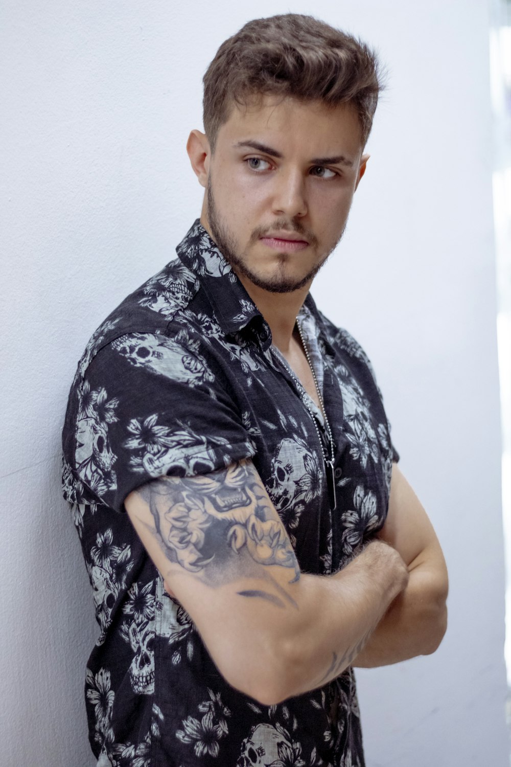 a man with a tattoo on his arm leaning against a wall