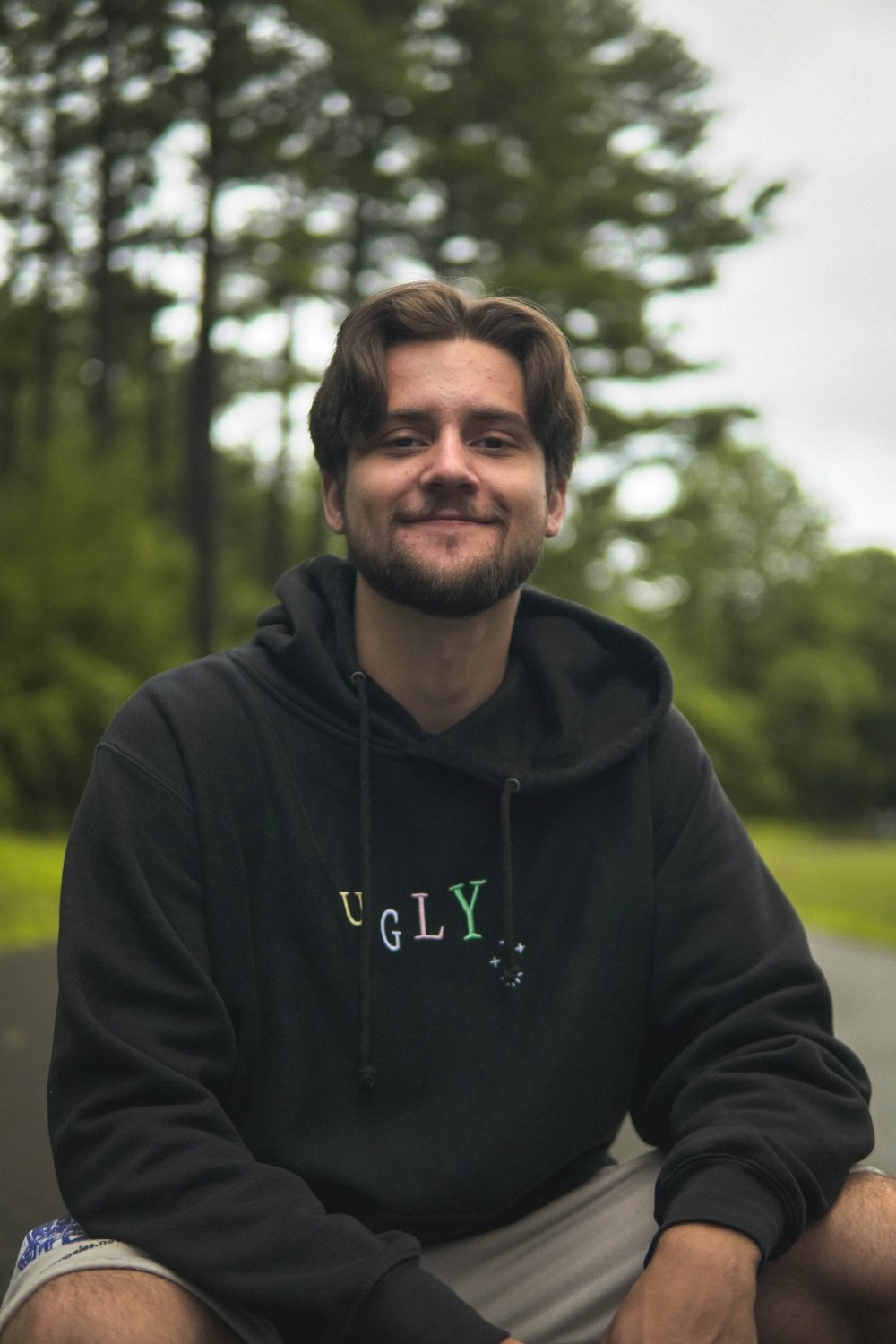 a man in a black hoodie sitting on a skateboard