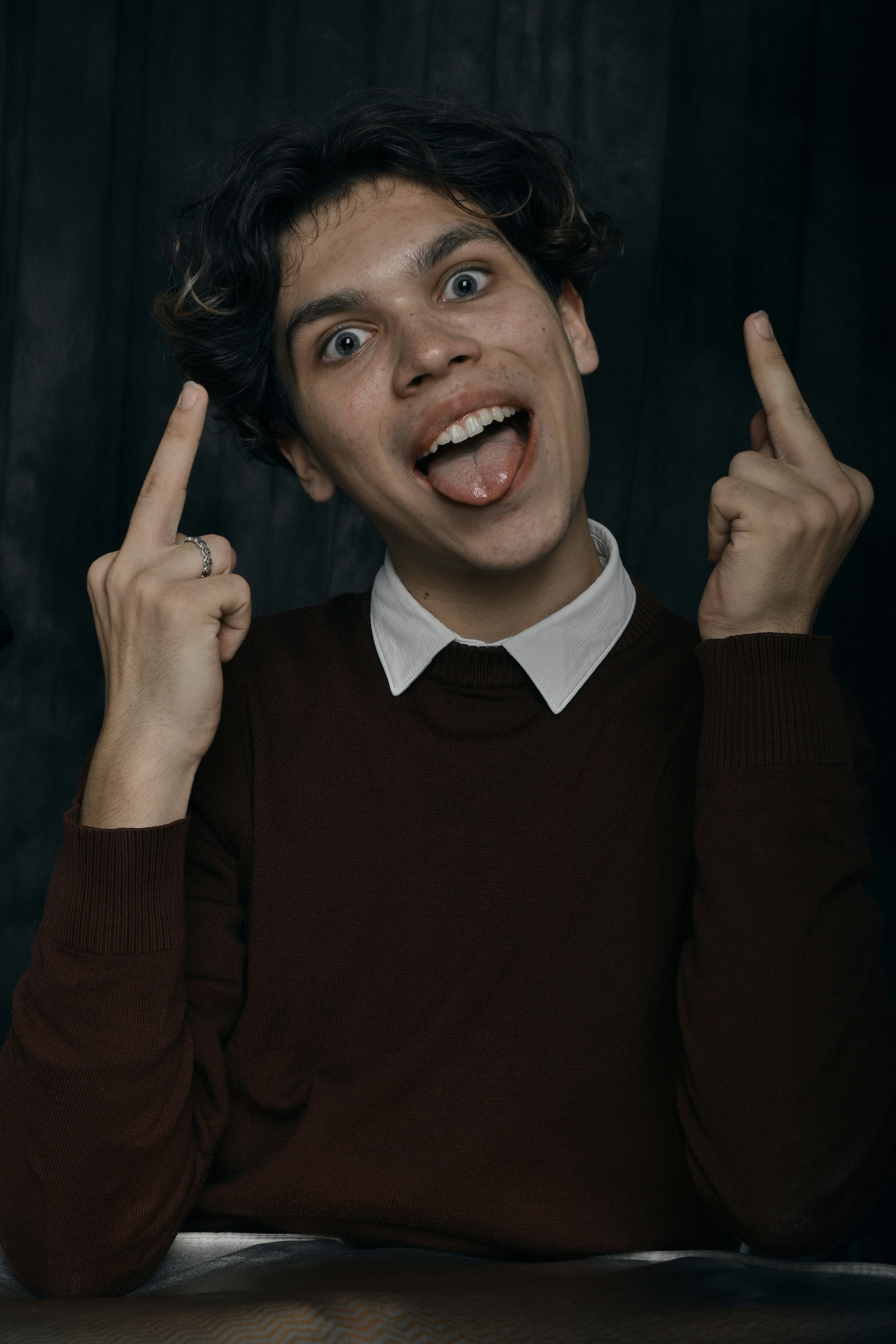 a young man making a silly face while sitting at a table