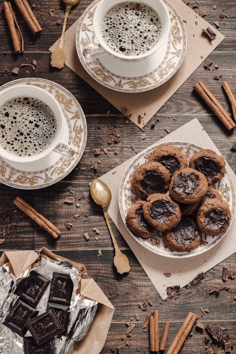 a table topped with a plate of cookies and cups of coffee