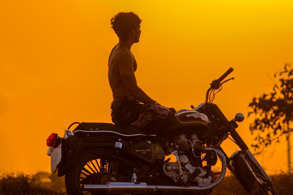 a man sitting on a motorcycle in the sunset