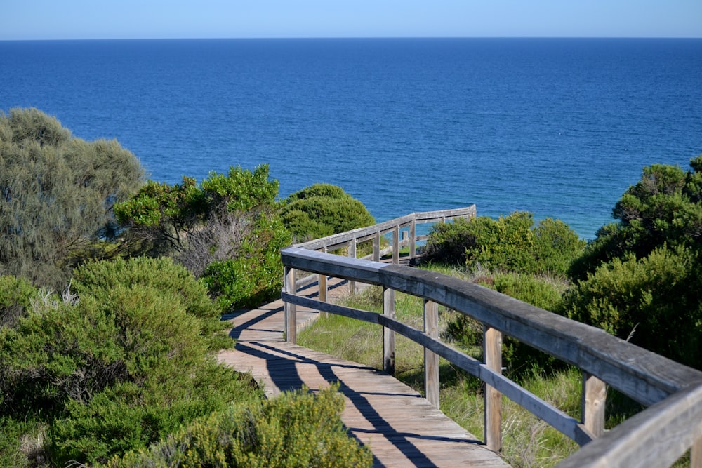 a wooden walkway leading to the ocean on a sunny day