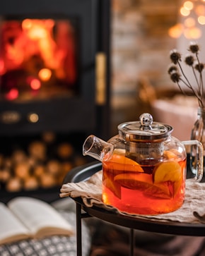a tea pot filled with tea next to a fire place