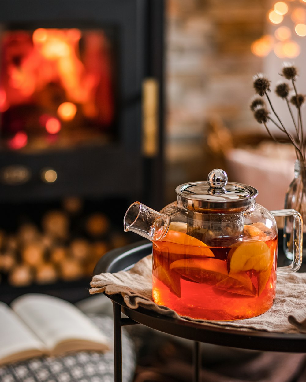 a tea pot filled with tea next to a fire place