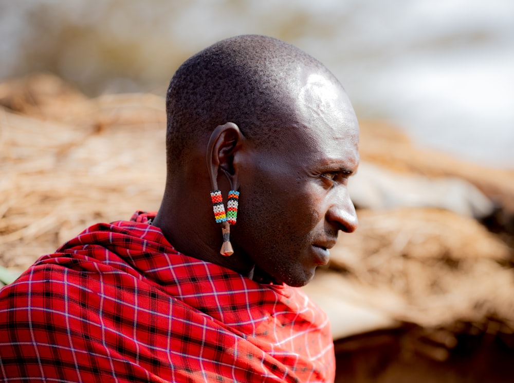 a man in a red and black shirt and earrings