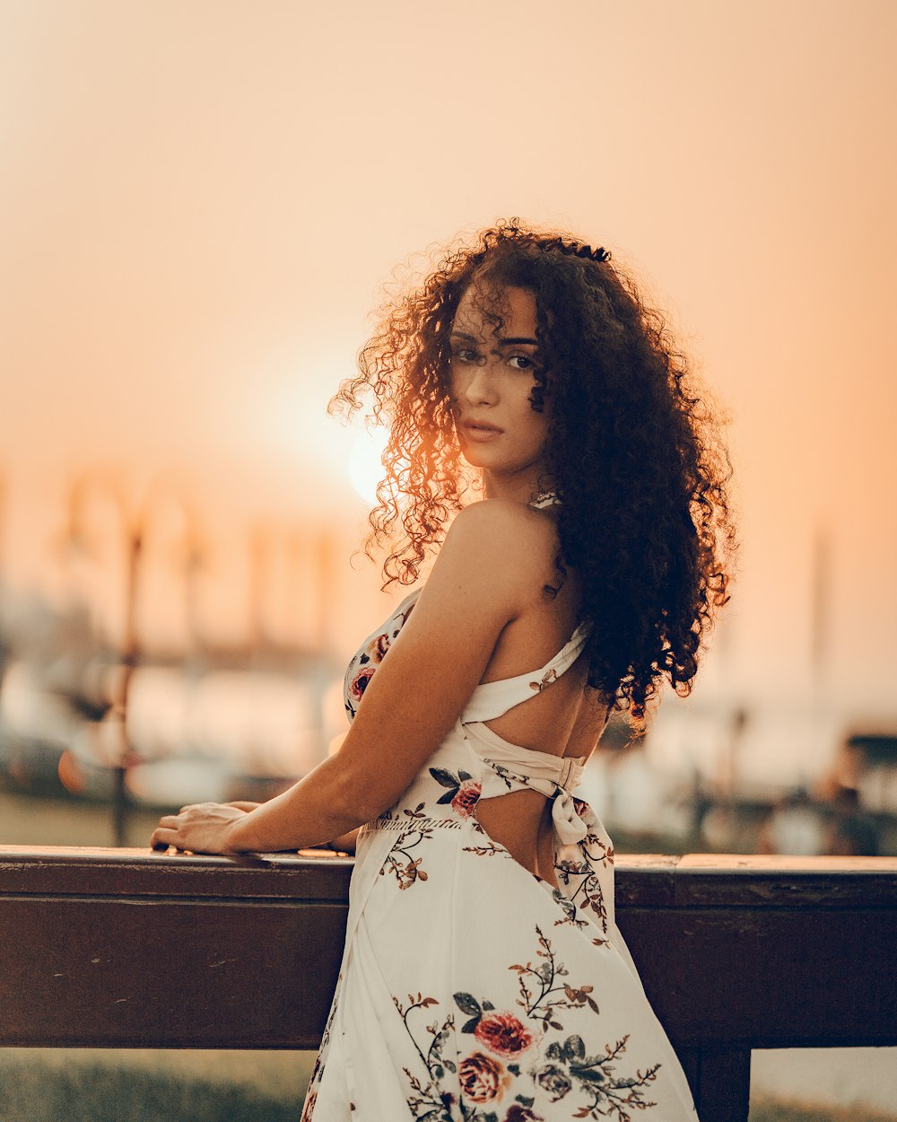 a woman in a floral dress leaning on a rail