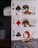Three playing cards featuring intricate designs and illustrations of figures resembling superheroes. The cards displayed are the King of Spades, the Jack of Diamonds, and the Queen of Clubs. Each card shows a uniquely illustrated character with detailed symbolic armor and weapons.