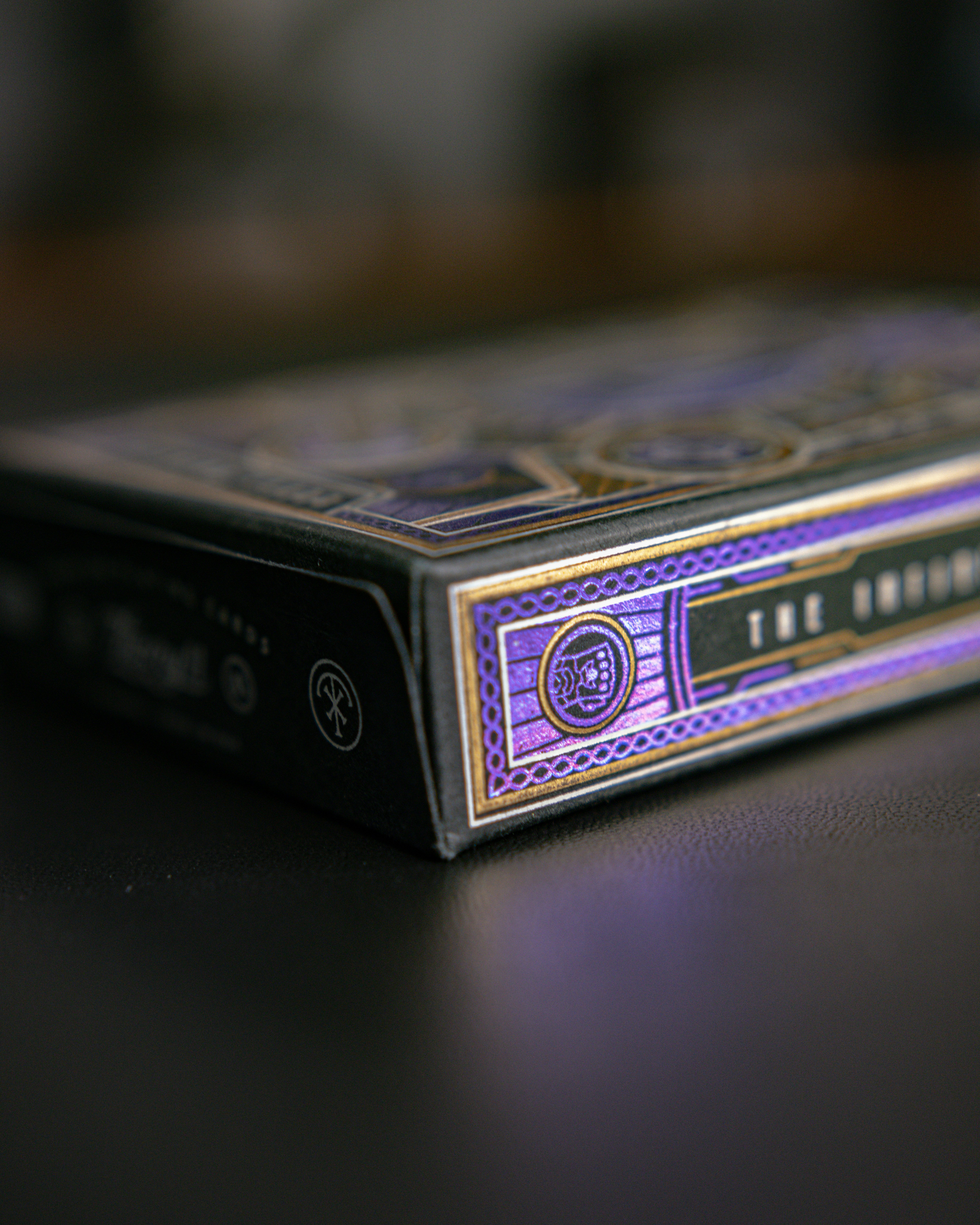 Black playing card box with intricate gold and purple designs.