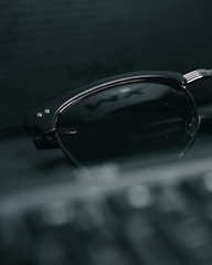 Minimalist shot of Dior sunglasses placed on a smooth black surface with a faint golden reflection.
