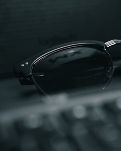 Minimalist shot of Dior sunglasses placed on a smooth black surface with a faint golden reflection.