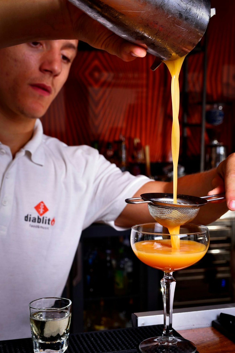 a man pouring a drink into a martini glass