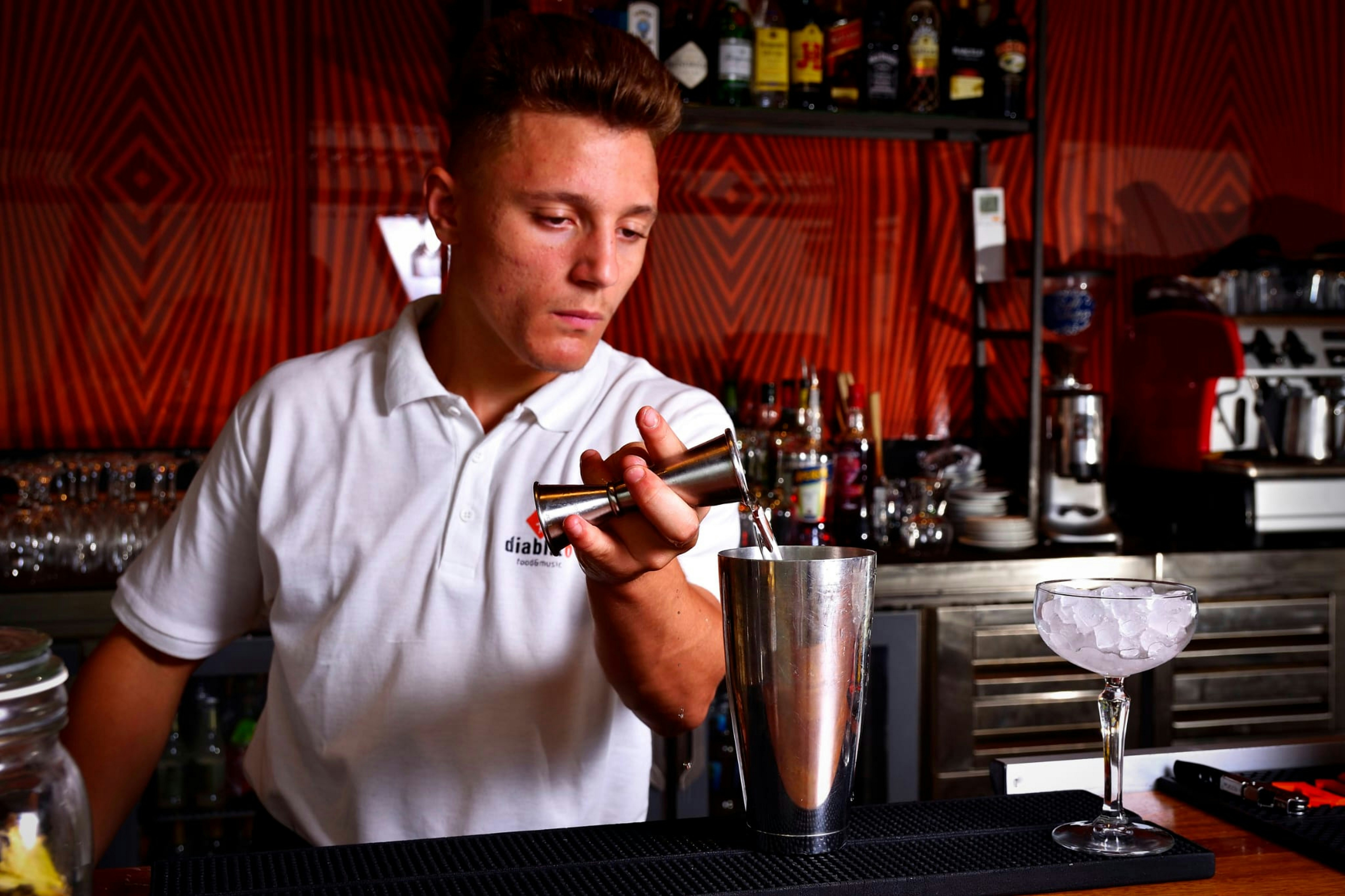 Bartender using a jigger and shaker - modern bar uniforms