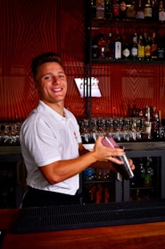 a man standing behind a bar holding a bottle