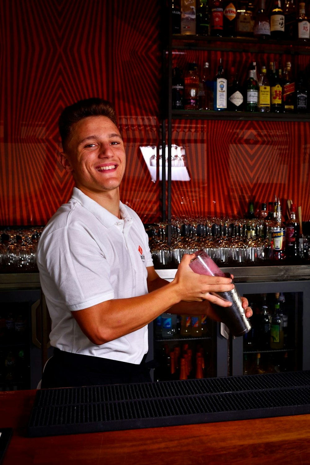 a man standing behind a bar holding a bottle