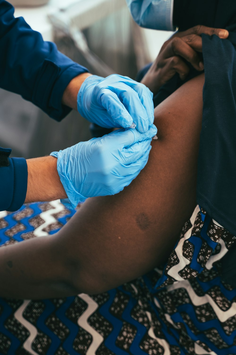 Eine Person mit blauen Handschuhen bekommt eine Impfung