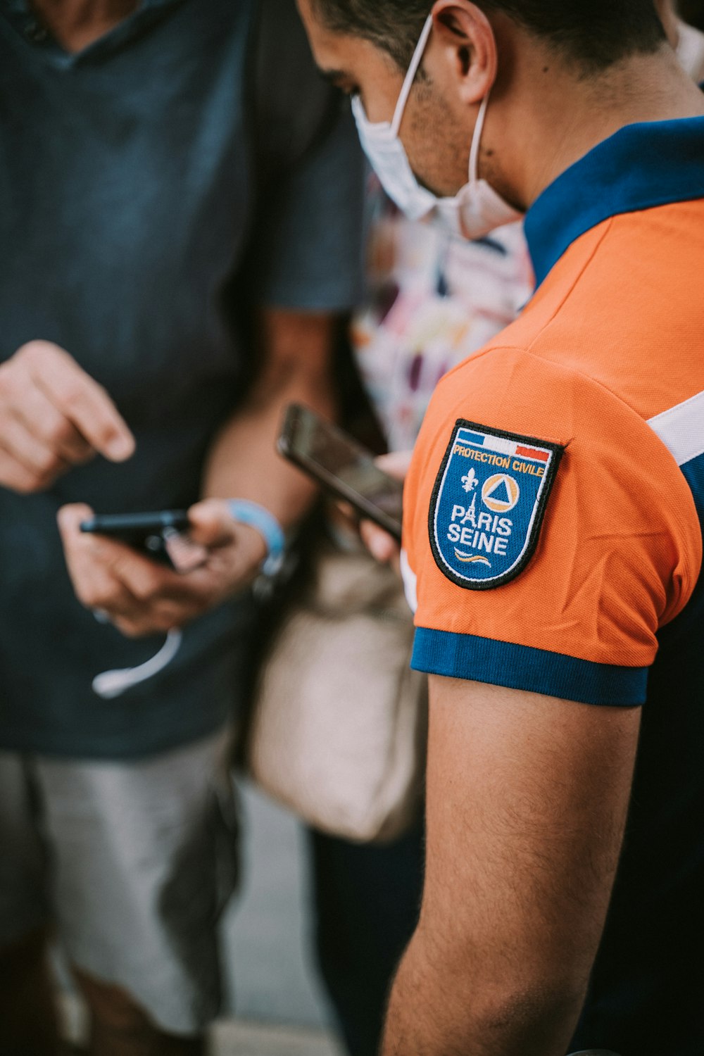 a man in an orange shirt looking at his cell phone