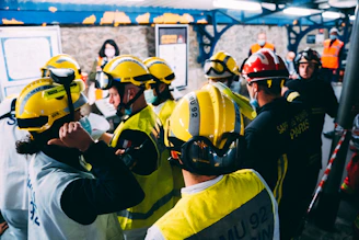 A diverse crew gathered around a table reviewing safety checklists with bright safety gear.