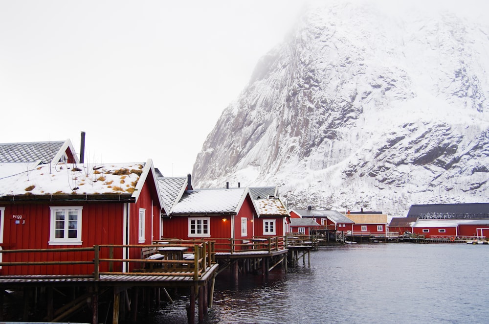 a group of red houses sitting next to a snow covered mountain