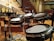 A set of electronic drums is positioned in an auditorium with tiered seating in the background. The room is spacious with wooden flooring and a series of black and white chairs organized in rows. The drum set, equipped with cymbals and multiple drum pads, is centrally placed on what appears to be a stage area.