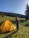 A smiling woman standing next to a 3x6 garden party tent in a sunny backyard.