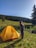 A smiling woman standing next to a 3x6 garden party tent in a sunny backyard.