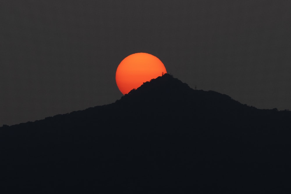 the sun is setting behind a mountain