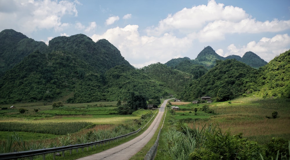 a dirt road in the middle of a lush green valley