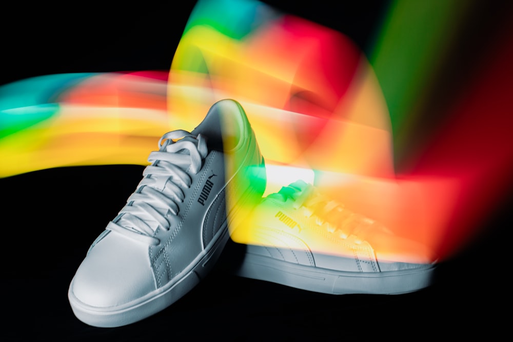 a pair of white sneakers with a rainbow background