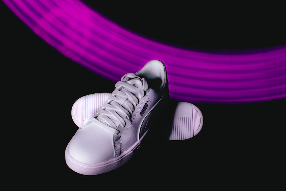 a pair of white sneakers sitting on top of a purple object
